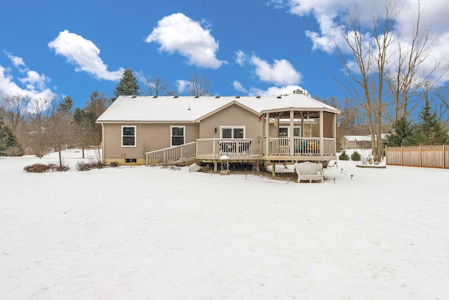 snow covered back of property featuring a deck