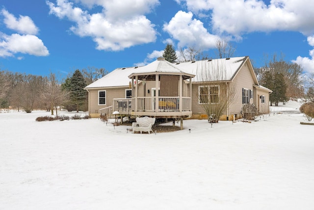 snow covered back of property featuring a wooden deck