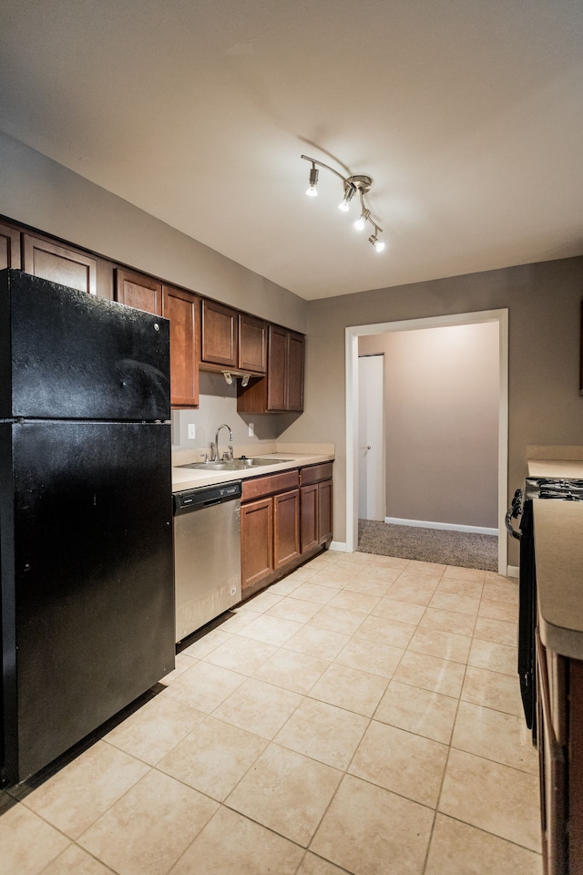 kitchen featuring sink, light tile patterned floors, black refrigerator, stainless steel dishwasher, and stove