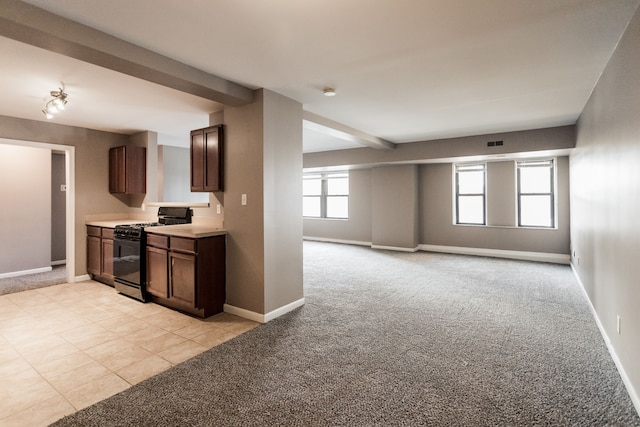 kitchen featuring light carpet, beam ceiling, and black range with gas cooktop