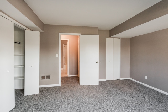 unfurnished bedroom with dark carpet and a closet