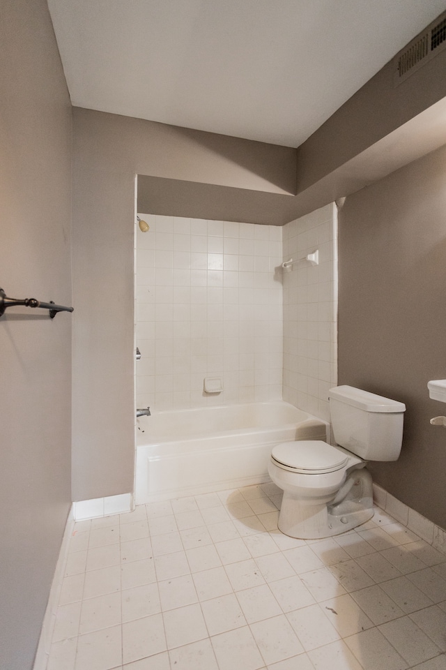 bathroom with tile patterned flooring, tiled shower / bath combo, and toilet