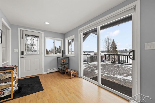 doorway to outside featuring a wealth of natural light, a baseboard radiator, and light hardwood / wood-style floors