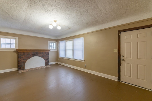 unfurnished living room with a brick fireplace, a textured ceiling, and dark hardwood / wood-style floors