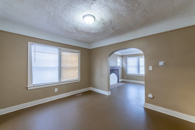 unfurnished room with a fireplace and a textured ceiling