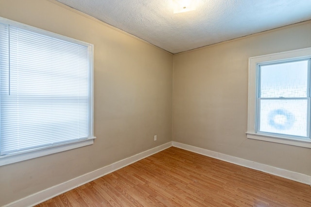 spare room featuring light hardwood / wood-style floors and a textured ceiling