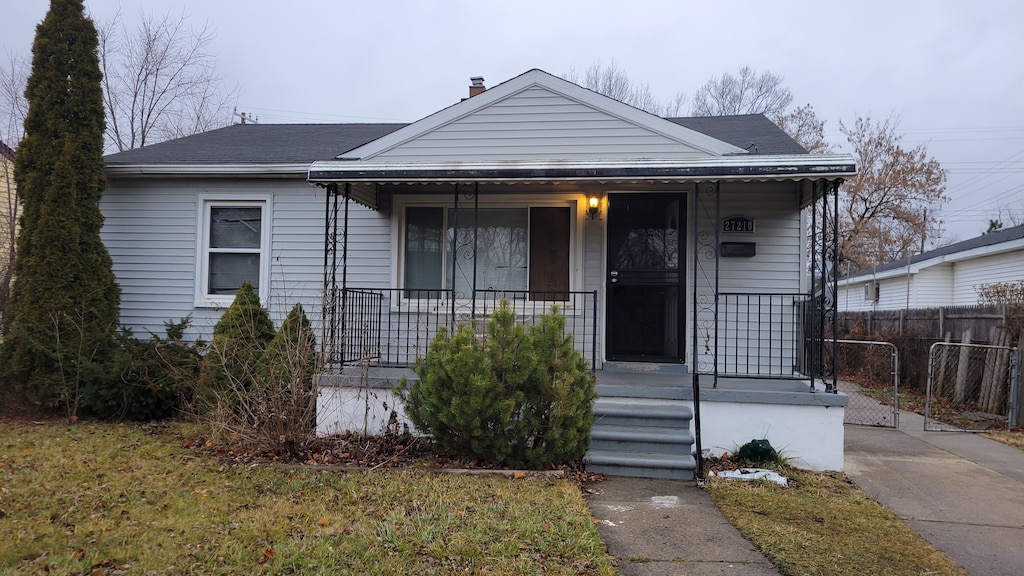 bungalow-style house featuring covered porch and a front yard