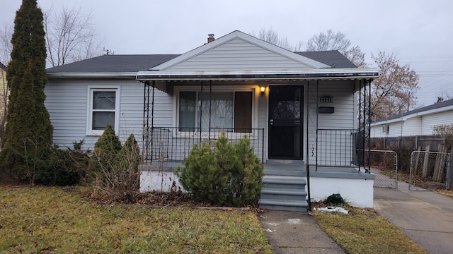 bungalow-style house featuring covered porch and a front yard