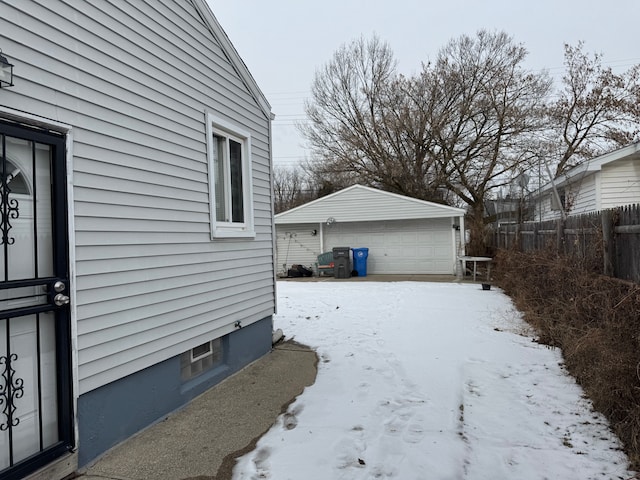 snow covered property with a garage and an outdoor structure