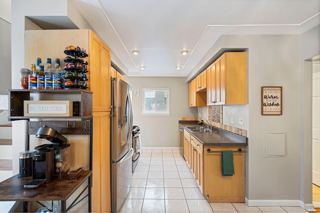 kitchen featuring appliances with stainless steel finishes, light brown cabinetry, sink, decorative backsplash, and light tile patterned floors