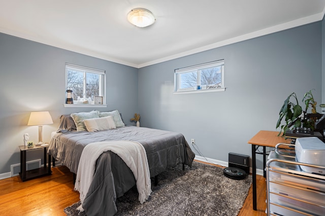 bedroom featuring multiple windows, crown molding, and wood-type flooring