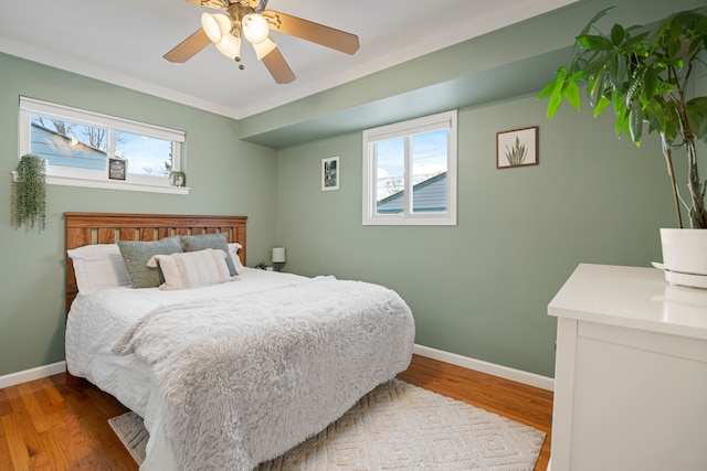 bedroom with multiple windows, hardwood / wood-style flooring, and ceiling fan