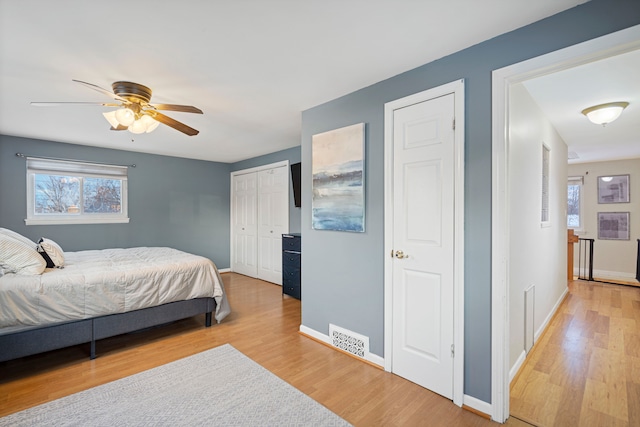 bedroom featuring multiple closets, ceiling fan, and light hardwood / wood-style floors