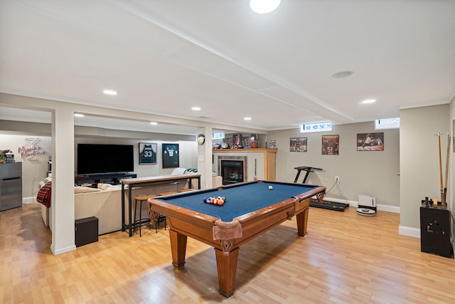 rec room with billiards, a tiled fireplace, and light wood-type flooring