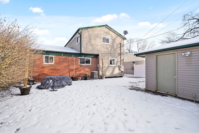 snow covered house featuring cooling unit and a storage unit