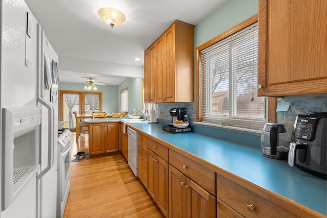 kitchen with sink, white appliances, light hardwood / wood-style flooring, and tasteful backsplash