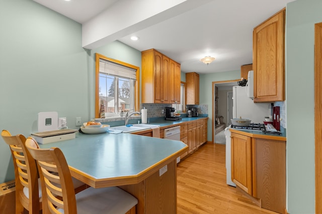 kitchen with light hardwood / wood-style floors, kitchen peninsula, backsplash, white appliances, and a breakfast bar