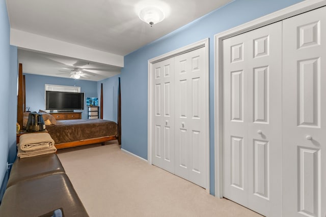 carpeted bedroom featuring ceiling fan and two closets