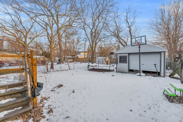 snowy yard featuring a garage and an outbuilding