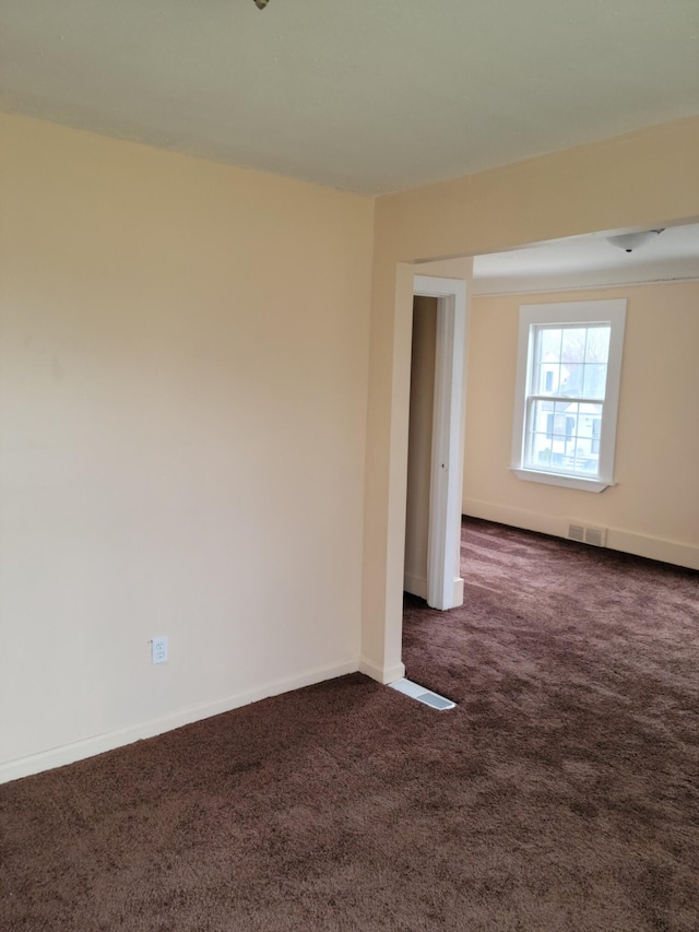 unfurnished room with dark colored carpet