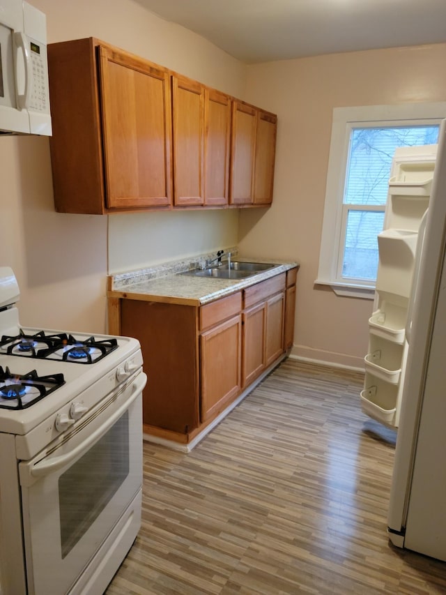 kitchen featuring sink, white appliances, and light hardwood / wood-style floors