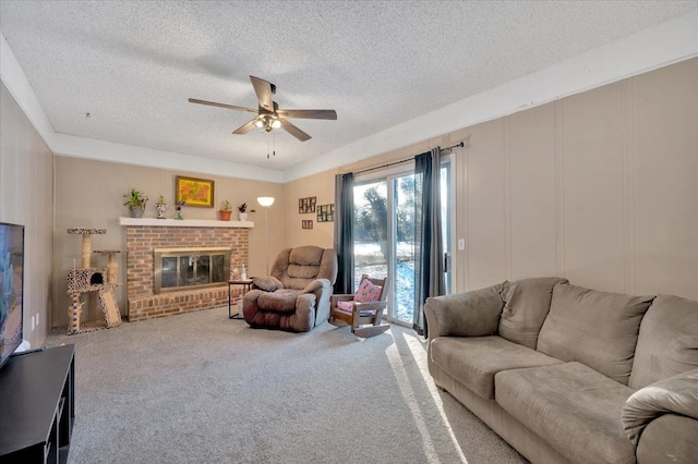 living room with a textured ceiling, ceiling fan, carpet, and a fireplace