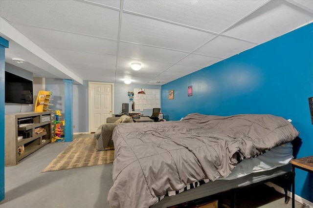 bedroom featuring a paneled ceiling and concrete floors