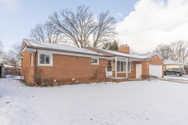 snow covered back of property with a garage