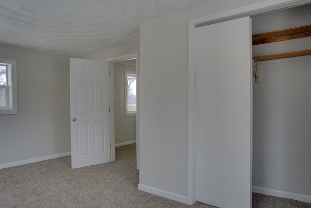 unfurnished bedroom featuring light colored carpet and a closet