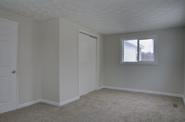 unfurnished bedroom with light colored carpet and a closet