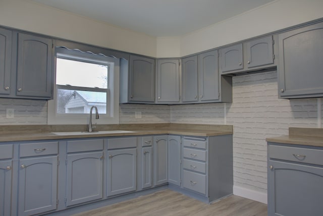 kitchen featuring gray cabinets, sink, backsplash, and light hardwood / wood-style floors