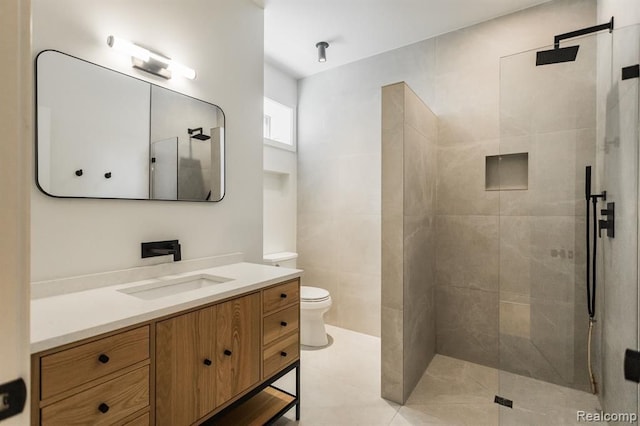 bathroom featuring tiled shower, vanity, toilet, and tile patterned flooring