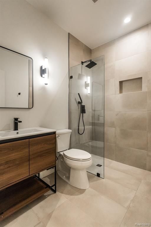 bathroom with tiled shower, vanity, and toilet