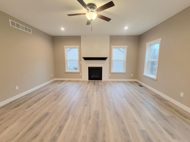 unfurnished living room with ceiling fan, light hardwood / wood-style floors, and a fireplace