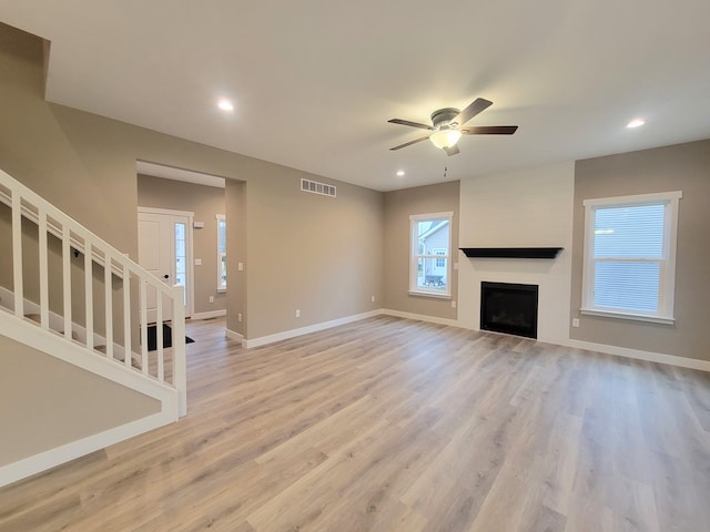 unfurnished living room featuring ceiling fan, light wood-type flooring, and a fireplace