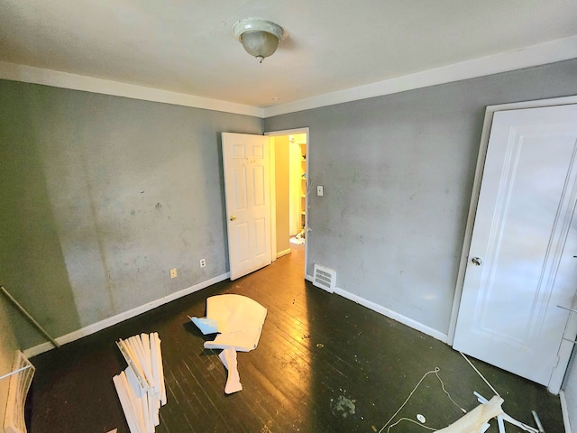 unfurnished bedroom featuring dark wood-type flooring and ornamental molding