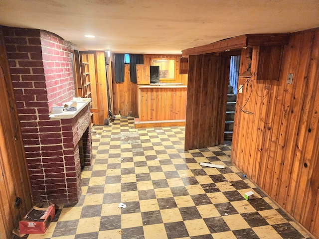 interior space with a brick fireplace and wooden walls