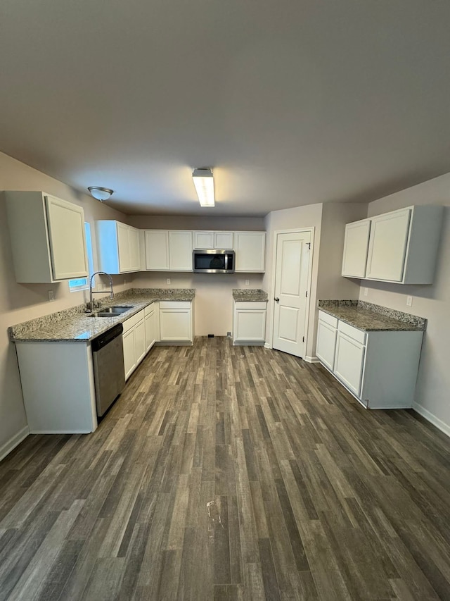 kitchen with dark wood-type flooring, appliances with stainless steel finishes, white cabinets, and sink