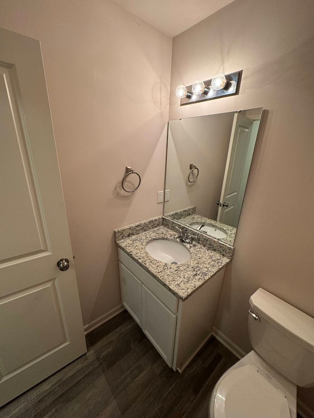 bathroom with toilet, hardwood / wood-style flooring, and vanity