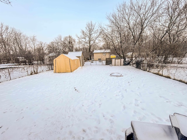 snowy yard featuring a storage shed