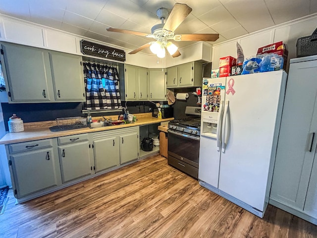 kitchen with ceiling fan, sink, stainless steel range with gas cooktop, dark wood-type flooring, and white fridge with ice dispenser