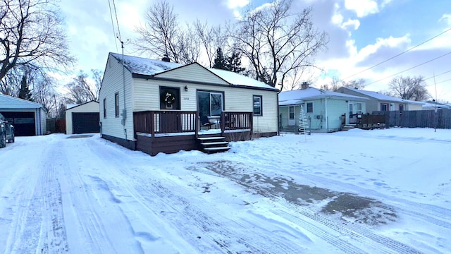 bungalow-style home featuring a garage, a deck, and an outbuilding