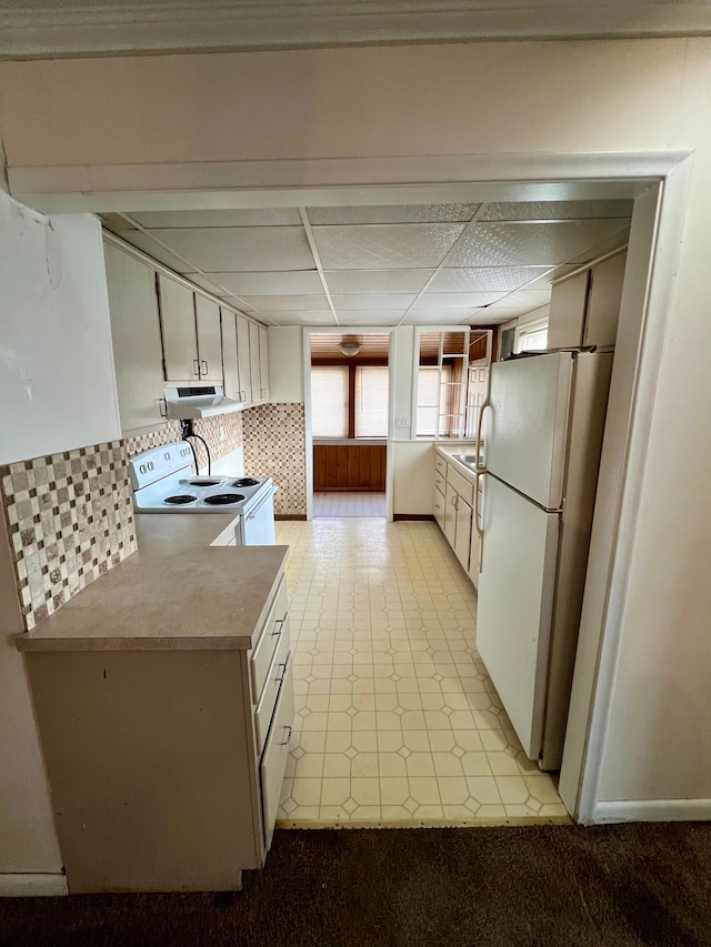 kitchen with backsplash, white appliances, white cabinetry, and a paneled ceiling