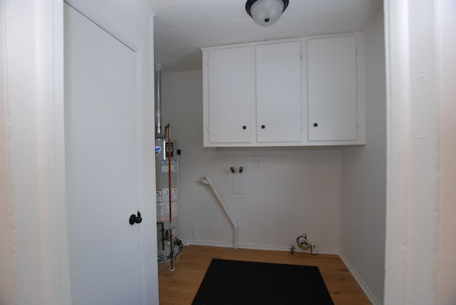 clothes washing area featuring gas water heater, cabinets, and light wood-type flooring