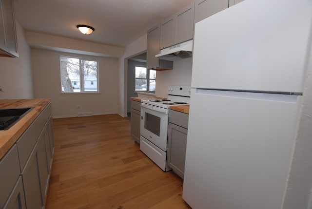 kitchen with white appliances, sink, gray cabinets, butcher block countertops, and light hardwood / wood-style flooring