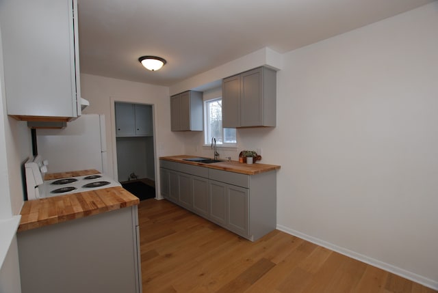 kitchen featuring sink, gray cabinets, white appliances, and butcher block counters