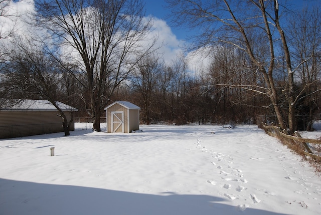 yard layered in snow featuring a storage shed