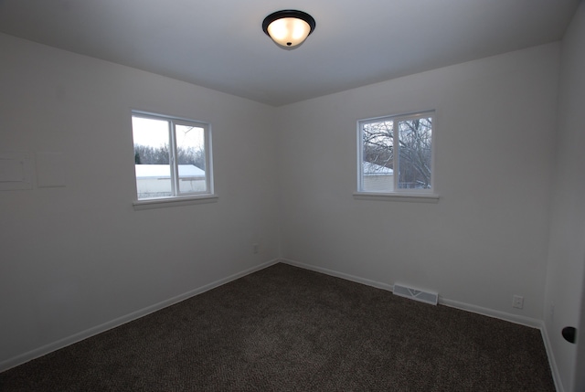 spare room featuring dark carpet