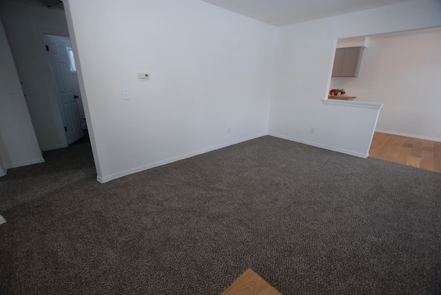 unfurnished room featuring dark colored carpet