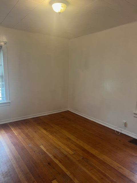 spare room with dark wood-style floors and baseboards
